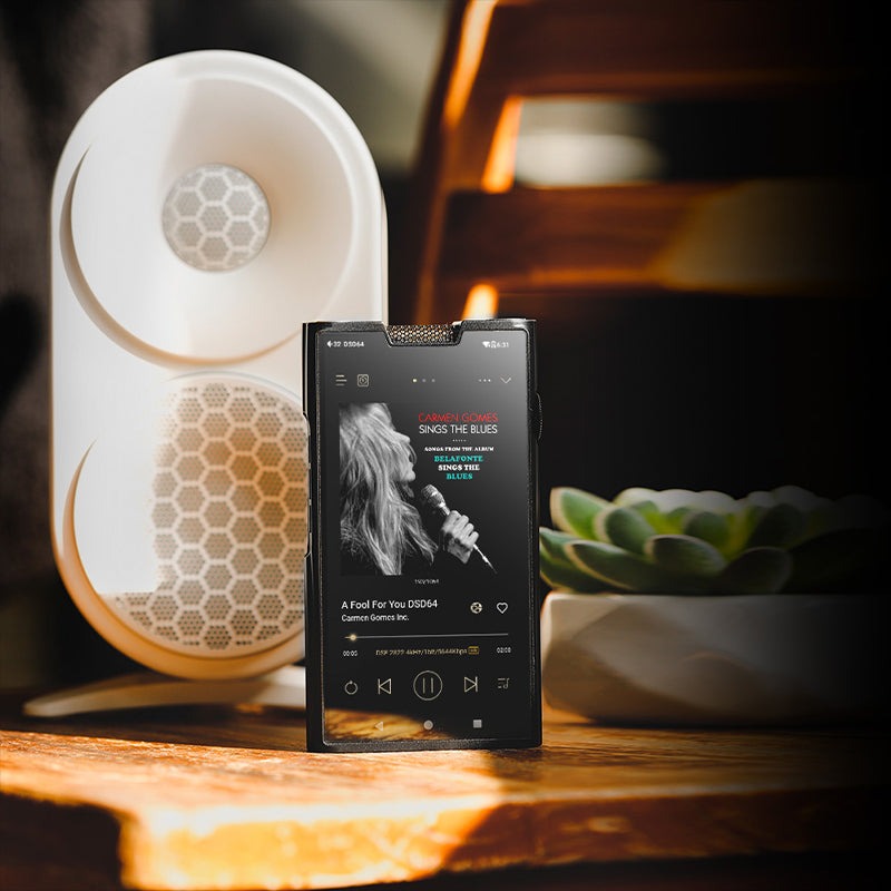 Shanling M8T on a wooden desk beside a speaker playing a DSD64 album