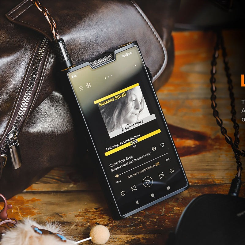 Shanling M8T playing a FLAC album on a wooden table next to a leather bag